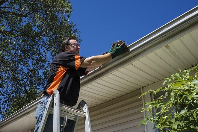 a damaged gutter being repaired by a professional in Fords